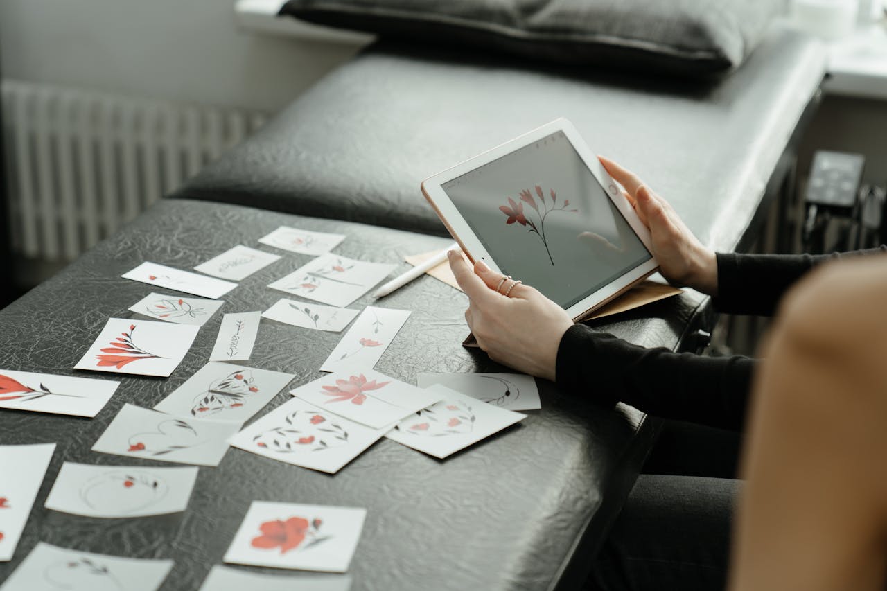 our-story Artist finalizing floral tattoo designs on a digital tablet in a studio setting.